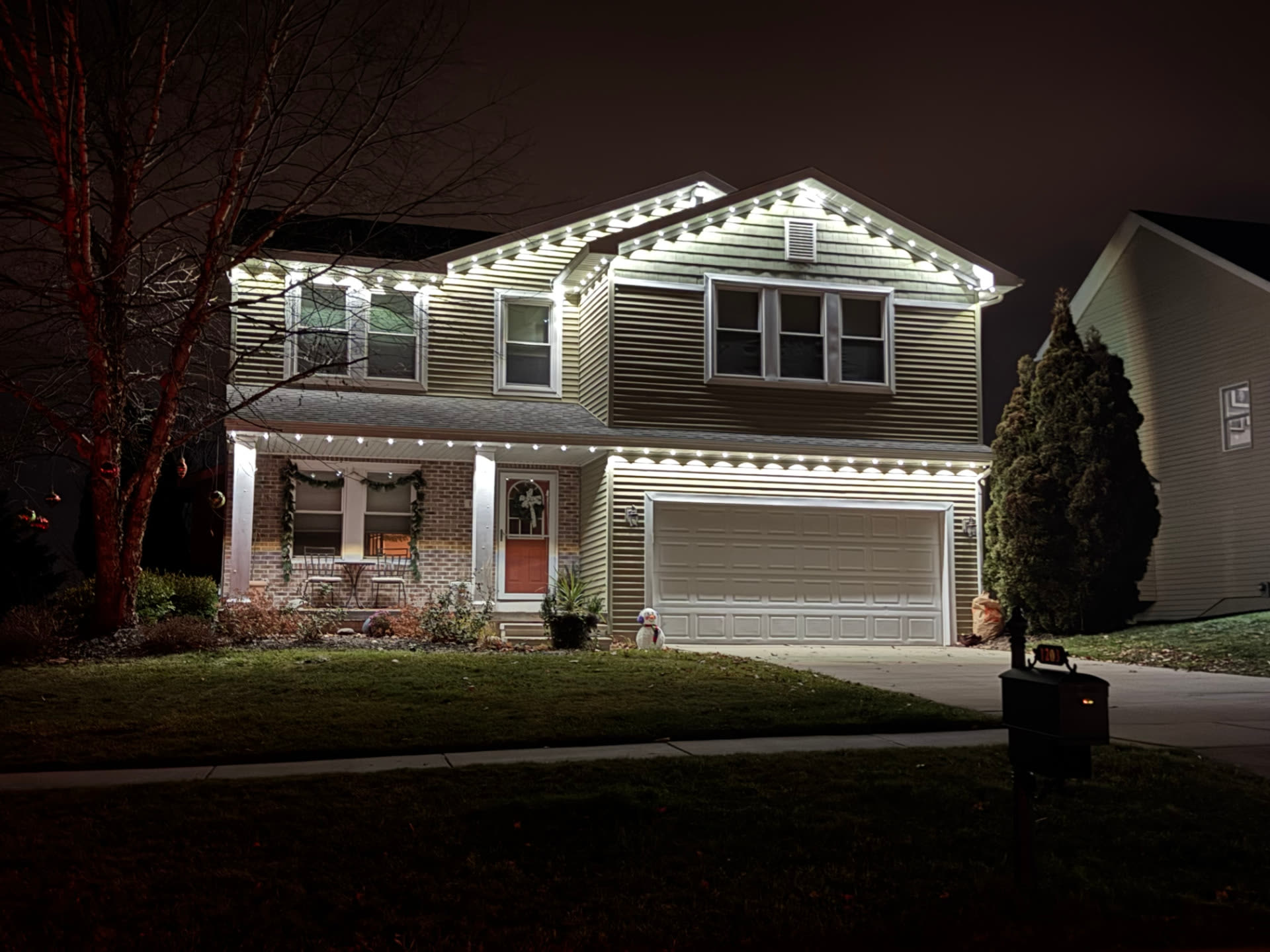 Two-story home with clean white lighting along the upper roofline, porch and garage