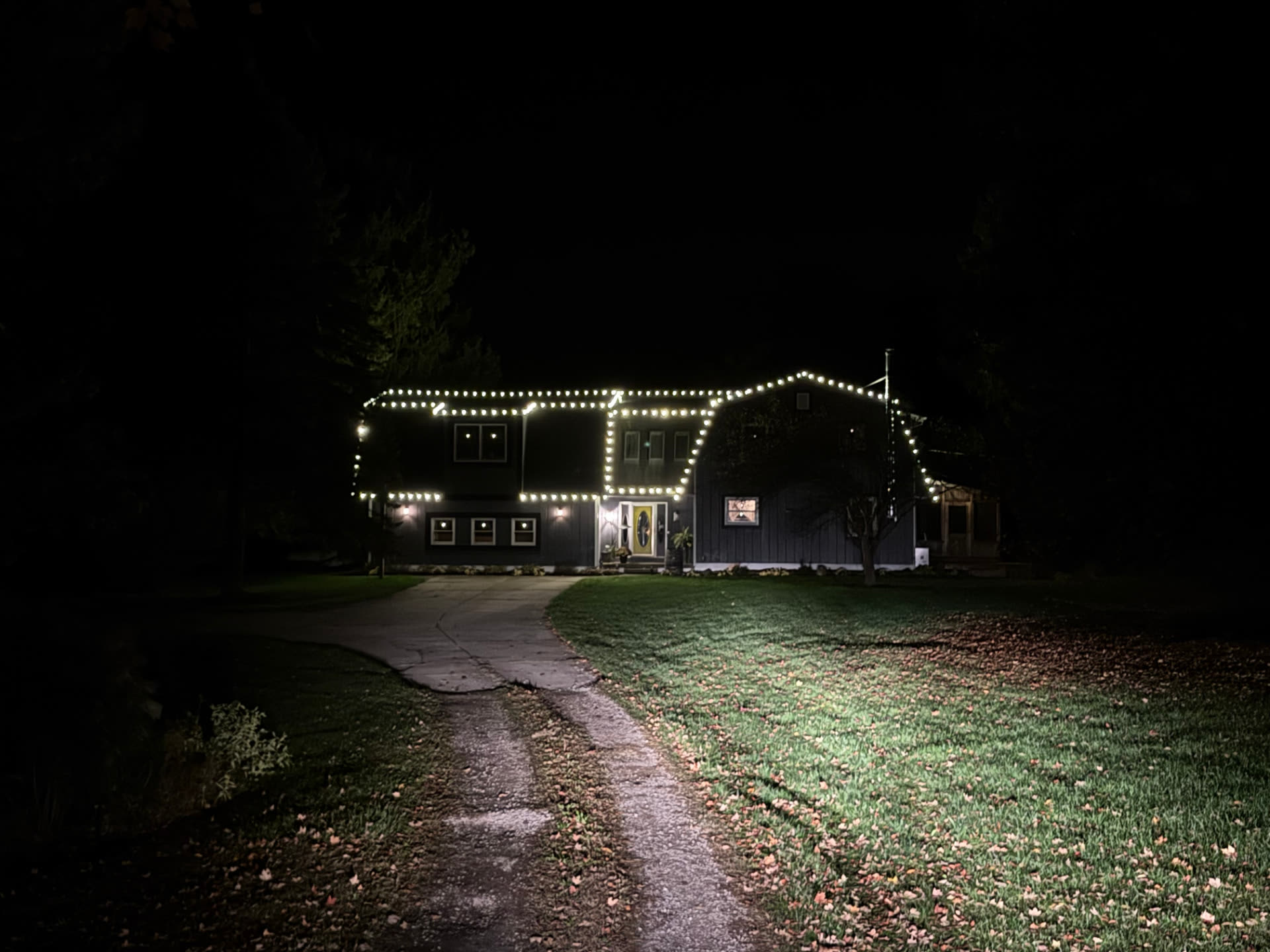 Large Greater Lansing home with warm white lights defining the roofline at night