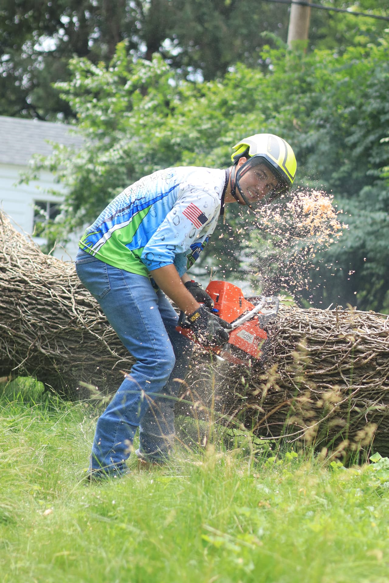 Kennan cutting a fallen tree limb with a chainsaw while working on a Lansing property
